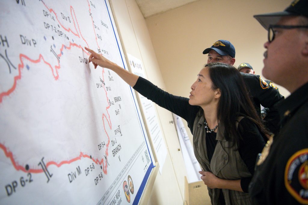 County officials reviewing a map during a COVID-19 briefing, discussing response strategies and resource allocation.