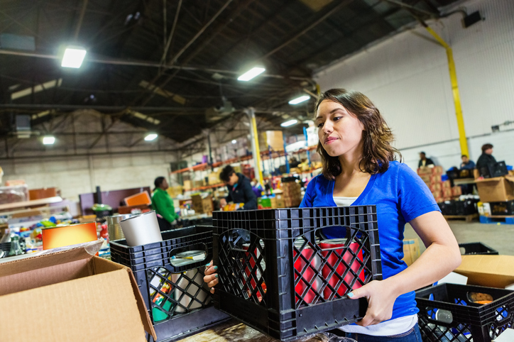 Young woman volunteering to organize donations in large food bank