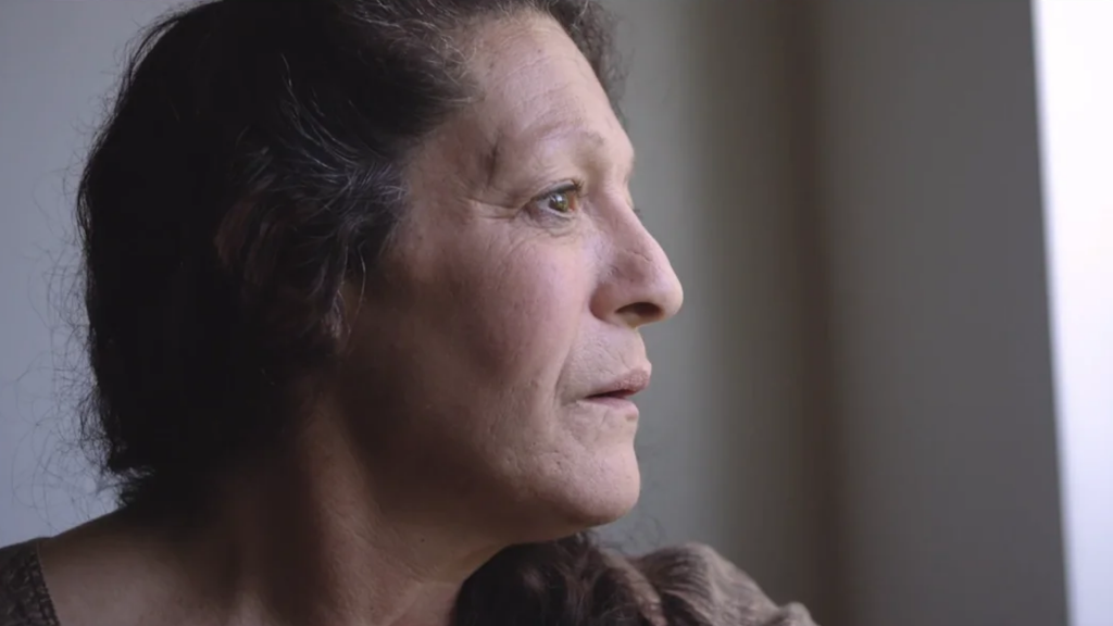 A woman gazes thoughtfully out a window, reflecting on the challenges of the COVID-19 pandemic.